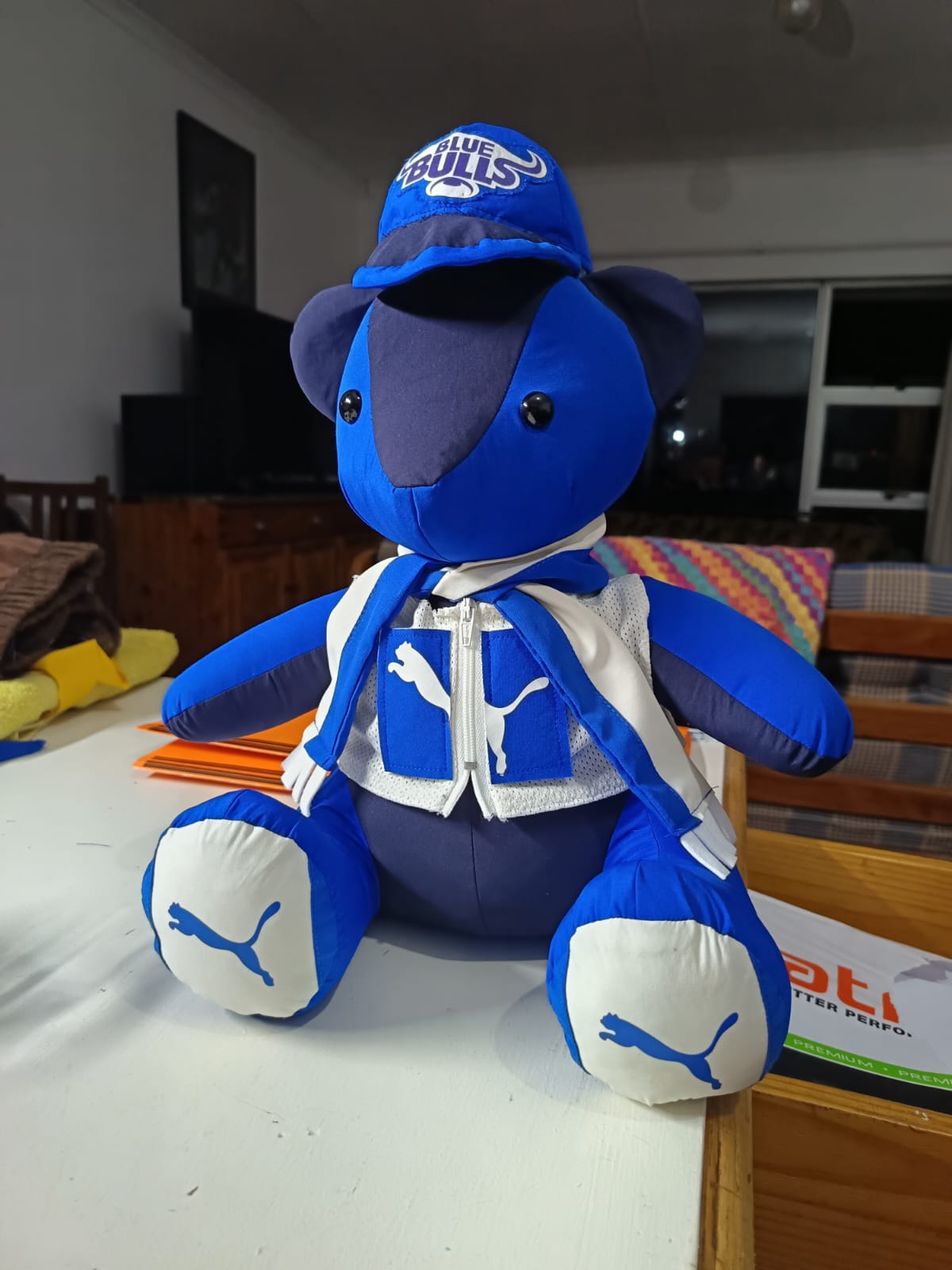 A blue teddy bear sewn from Blue Bulls kit, wearing a mesh vest with a working zip, a cap and a team scarf